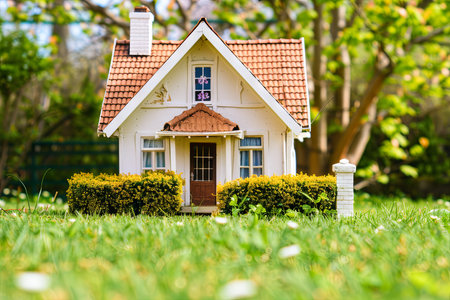 A small white house stands prominently on a vast expanse of lush green field under a clear blue sky. The house is surrounded by vibrant greenery, emphasizing its quaint charm against the natural backdrop.の素材