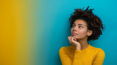A woman wearing a bright yellow sweater is gazing upwards, her eyes fixed on something above her. She appears thoughtful and engaged, with a slight expression of curiosity on her face.の素材