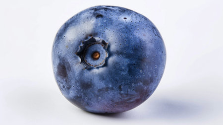 A detailed view of a single blueberry resting on a plain white background. The blueberry is rich in color and texture, showcasing its round shape and small dimpled surface. The simplicity of the white background enhances the vibrancy of the fruits deep blue hue.の素材