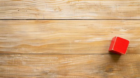 A red box is placed on top of a wooden table, creating a simple yet visually striking composition. The contrast between the vibrant red color of the box and the warm tones of the table creates a visually appealing scene.の素材
