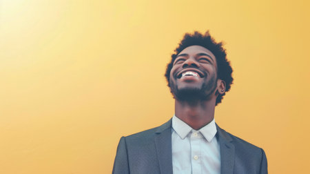 A man dressed in a suit is smiling as he gazes upwards, showing a sense of positivity and enthusiasm. His posture exudes confidence and happiness in a professional setting.の素材