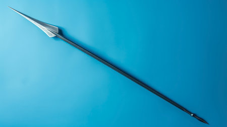 A single steel spear lies on a blue background, its sharp point facing the lower right of the image. The spear is a traditional weapon with a long, slender shaft and a sharp, pointed head. The spear is depicted in isolation on a solid, blue backdrop, emphasizing its sleek and formidable design.の素材