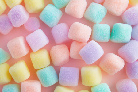 Soft pastel-colored marshmallow squares are scattered across a light pink surface, creating a playful and inviting look.の素材