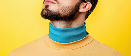 A man showcases his stylish turtleneck sweater with a blue collar against a bright yellow background.の素材
