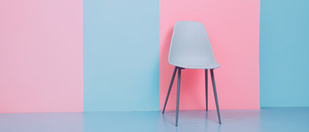 A minimalist chair is placed in front of a pastel blue and pink wall creating a modern and stylish interior design element.の素材