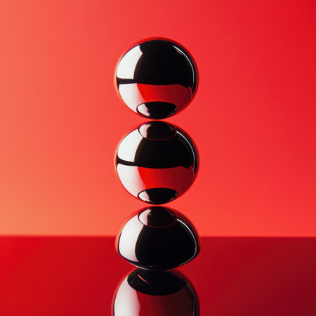 Three glossy black spheres are meticulously balanced on top of each other set against a vivid red background creating a striking visual contrast.の素材
