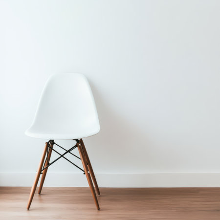 A modern white chair rests against a clean white wall showcasing minimalist design and natural wood accents in a bright interior space.の素材