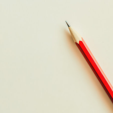 A red pencil lays on a blank surface ready for sketching or writing. The sharpened tip invites inspiration and creativity in artistic endeavors.の素材