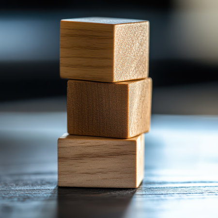 Three wooden blocks are neatly stacked on a dark table surface showcasing their natural texture and grain in soft lighting.の素材