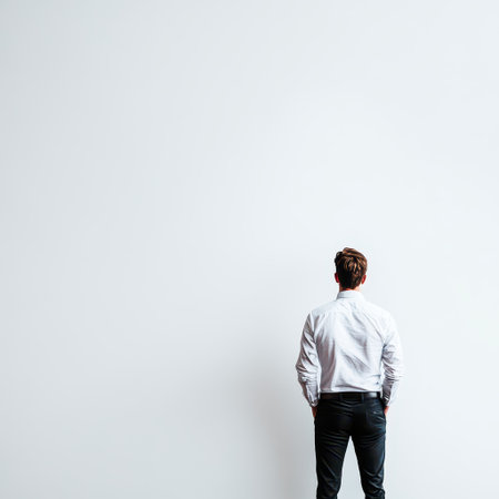 A person is standing alone hands in pockets facing a blank wall. The setting conveys a sense of contemplation and solitude.の素材