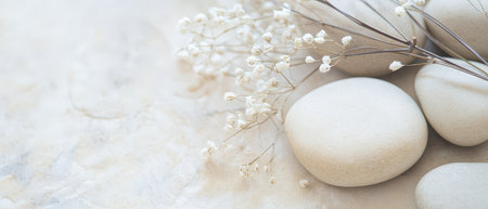 Smooth round stones are arranged alongside small delicate white flowers creating a tranquil and serene atmosphere that invites relaxation.の素材