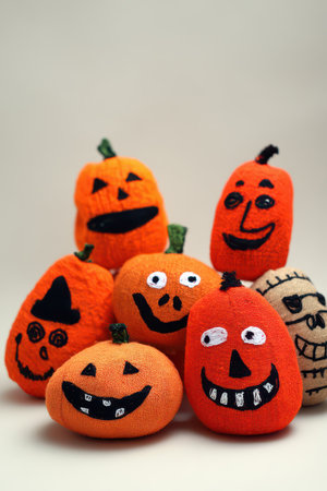 A collection of vibrant orange pumpkins with unique smiling faces displayed against a neutral background.の写真素材