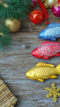 Colorful fish decorations in red blue and yellow sit on wooden surface among ornaments evoking a joyful holiday spirit and fun vibes.の素材