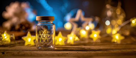 A glass jar displays a glowing atom surrounded by twinkling lights and festive decorations celebrating the New Year with a touch of science.の素材