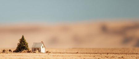 A small house stands lonely in a vast desert with a tiny Christmas tree nearby marking a unique New Year moment amid expansive minimalism.の素材