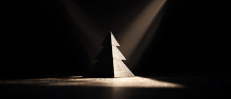 A uniquely shaped tree silhouette softly glows against a dark backdrop creating a serene festive New Year atmosphere.の素材