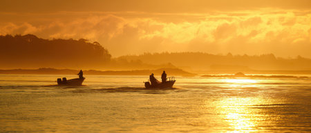 As the sun rises crabbers quietly navigate the water reflecting the beauty of a new year and the promise of fresh catches.の素材