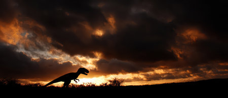 A majestic allosaurus stands against a vivid sunset sky capturing the spirit of adventure for the New Year with dramatic clouds and warm colors.の素材