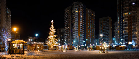 Twinkling lights illuminate a snowy city square filled with holiday decorations and a towering Christmas tree on a joyful winter evening.の素材