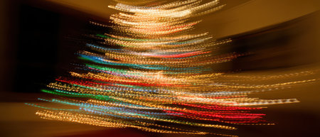 Colorful lights swirl around a Christmas tree creating a dreamy atmosphere. The warm glow fills the room celebrating the holiday spirit.の素材