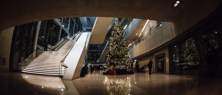 A stunning New Year setup features a tall decorated tree in a bright sleek building. Steps lead to festive gatherings filled with joyful spirits.の素材