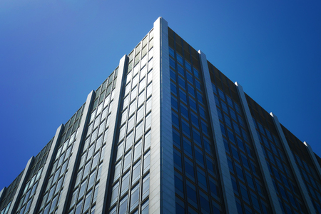 Facade of an office building, made of glass and steel with reflections of blue sky in San Francisco,...