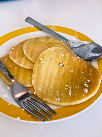 Pancakes with honey, spoon, fork on dish on tableの写真素材