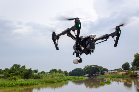 Professional camera drone flying on river and sky :  Drone black coverの写真素材