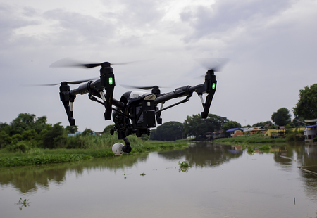 Professional camera drone flying on river and skyの写真素材