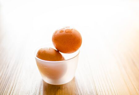 Fresh eggs in a cup on wooden floor.の写真素材