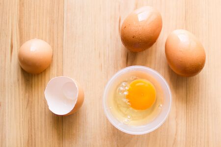 Fresh eggs in a cup and egg shell on wooden floor.の写真素材