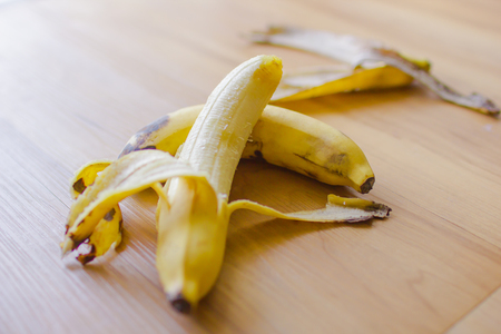 Two banana with banana peel on wooden floor.の写真素材