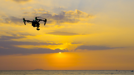 Professional camera drone flying on sea with sunset at twilight.の写真素材