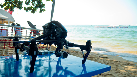 Professional camera drone on beach with sea background.