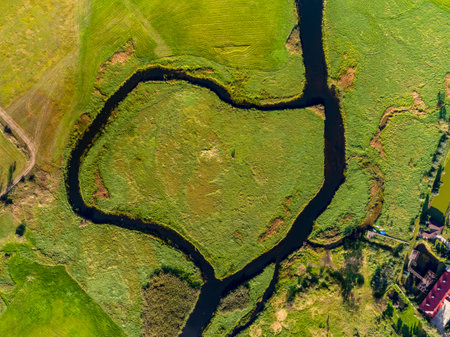 Aerial view of a small river in the middle of a green meadowの写真素材