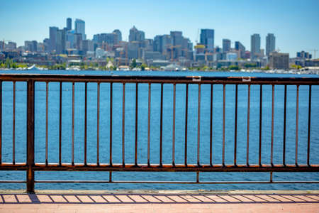 Sun over downtown Seattle with Elliott Bay and a guard rail in the foreground. Seattle downtown Seattle with Elliott Bay and a guard rail in the foreground. Empty skies.の写真素材