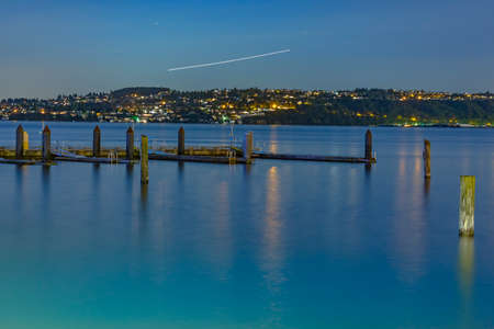 Plain trails at night with the dock and old wooden pillars. The bay in Tacoma Washington at sunset and into nightfallの写真素材