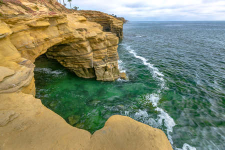 Caves on the coast of Point Loma with high tide waters. The California coast on a late afternoon during the summerの写真素材