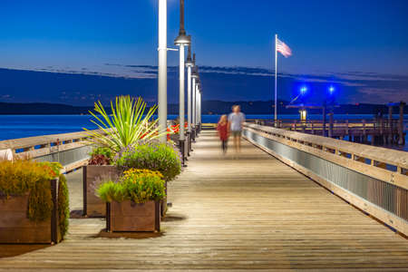 Rustic pier in Tacoma with unrecognizable couple . The bay in Tacoma Washington at sunset and into nightfallの写真素材