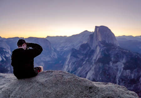 Glacier Point and view of Half Dome with photographer. Sunrise views from Glacier Point up to the very edge of the cliffの写真素材