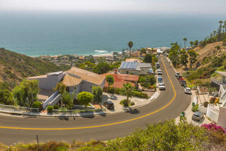 Coastal views of homes in Laguna Beach California looking downhill in residencial neighborhood. Wide curved uphill road in Laguna Beach California during a sunny day on the coastの写真素材