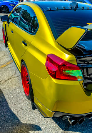 Metallic yellow car with large spoiler and red rims. Custom cars in Southern California summer 2017の写真素材