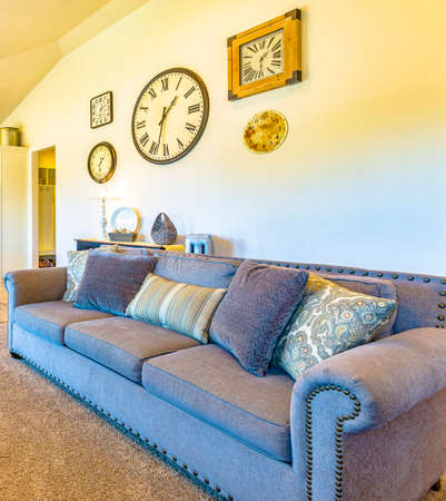Clocks on the wall above a sofa