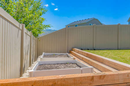 Empty growbeds in clean backyard with lawn