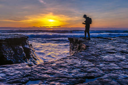 Silhouette man with camera on the coastの写真素材