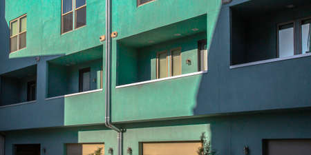 Sunlit building with balconies and glass windowsの写真素材
