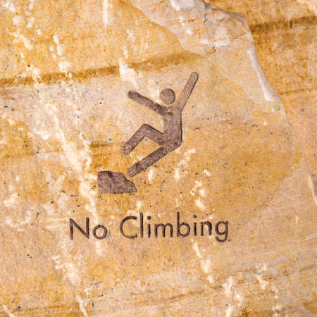 Brown rock engraved with no climbing sign