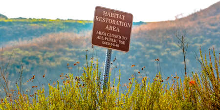 Habitat restoration area sign on a grassy mountainの写真素材