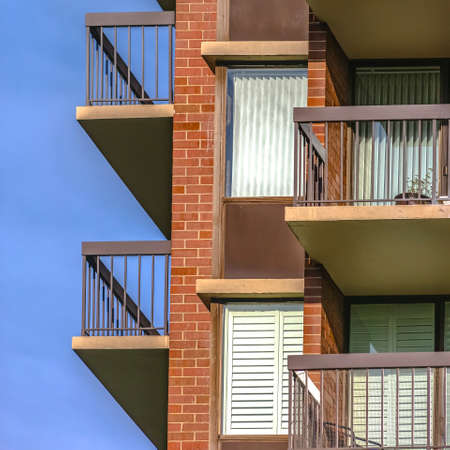 Sunlit balconies of a red brick buildingの写真素材