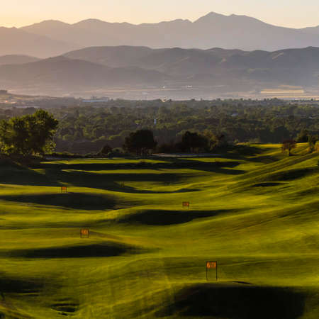 Vast golf course with view of trees and mountainの写真素材